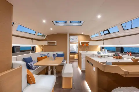 Jeanneau Sun Odyssey 455: bright saloon with light wood finish, overhead hatches, dining table and galley to starboard