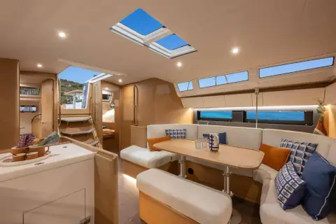 Jeanneau Sun Odyssey 455: saloon seating with blue cushions, folding table, hull windows and opening roof hatches