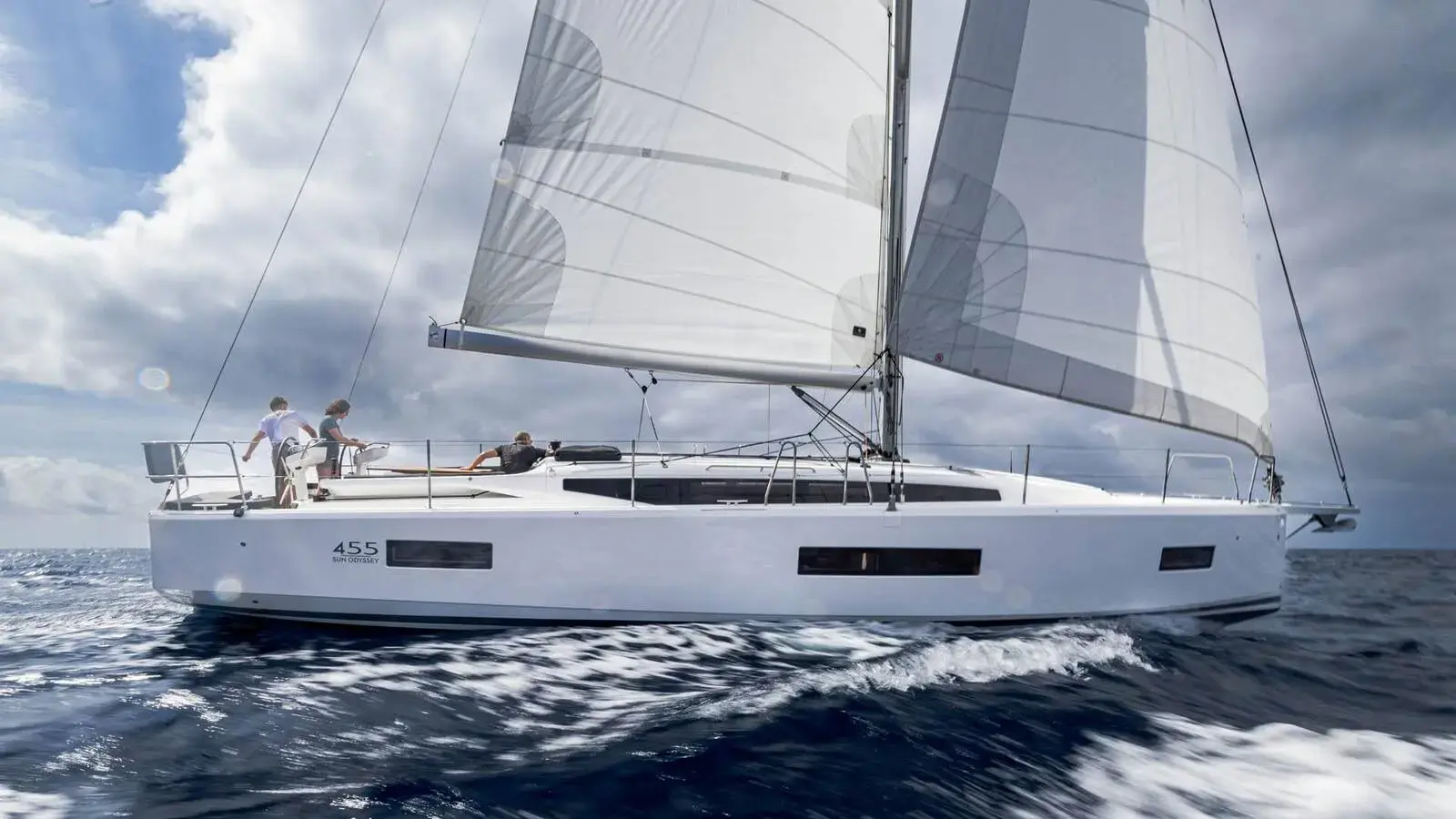 Jeanneau Sun Odyssey 455: white hull under full main and genoa, heeling in choppy open water with crew aboard