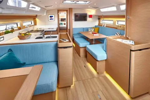 Jeanneau Sun Odyssey 490: wide view of saloon and galley with light oak joinery, blue seating and LED strip lighting