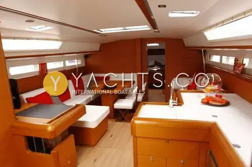 Jeanneau Sun Odyssey 509- 3 Cabins: saloon looking forward with red and white upholstery, dining table and galley counter