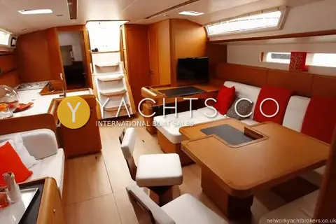 Jeanneau Sun Odyssey 509- 3 Cabins: wide saloon view with red cushions, chart table with screen and companionway steps