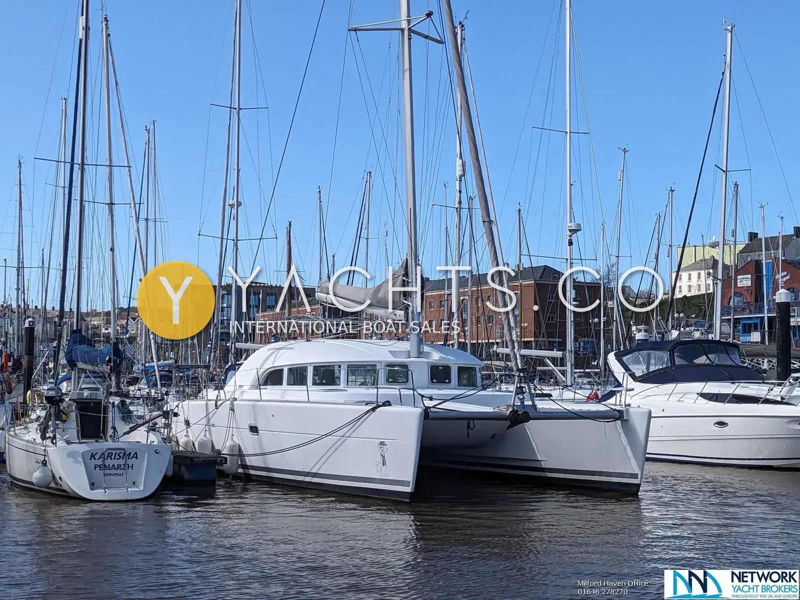 Lagoon 380: white catamaran moored stern-on in a Milford Haven marina among yachts under blue sky