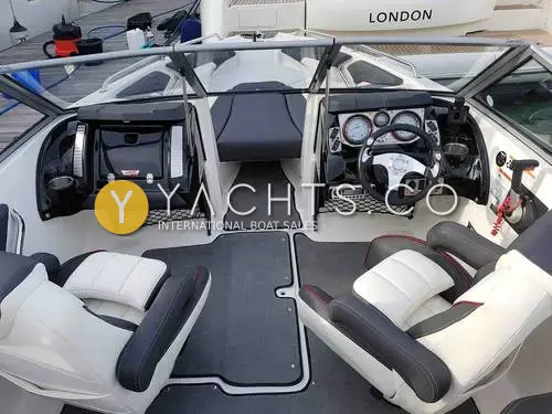 Larson 2300 LSR: cockpit from aft showing two white and grey helm seats, grey carpet and open walkthrough windscreen