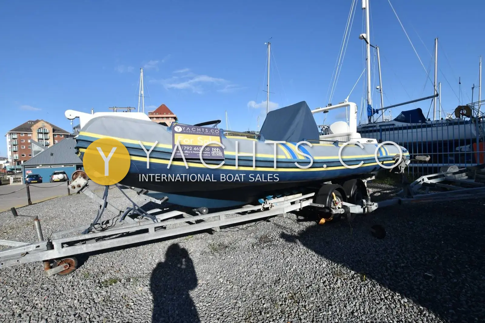 Marlin 640 FB Rib: port side of the grey RIB with yellow and blue tube stripes, on her trailer ashore
