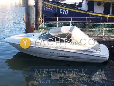 Maxum 2100 SC: white hull afloat alongside a pontoon with the camper canvas fitted over the cockpit