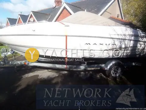 Maxum 2100 SC: hull on her single axle launching trailer, strapped down beside houses
