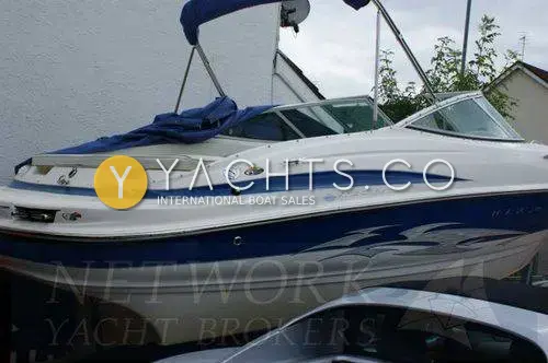 Maxum 2100 SC: port side of white and blue hull with swept graphics, on trailer beside a house
