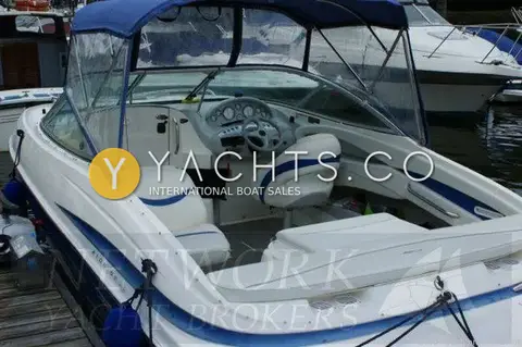 Maxum 2100 SC: cockpit under blue canopy with helm dash, blue-trimmed seats and engine cover sun pad