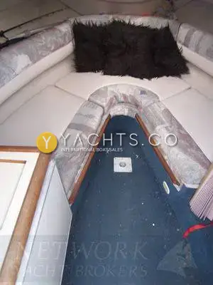 Maxum 2300 SC: forward cabin berth with patterned upholstery and blue carpeted floor