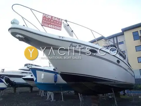 Maxum 3000 SCR: bow view ashore in a boatyard on stands, hull name Just Right, broker sign on rail