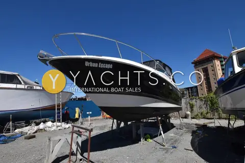 Monterey 245 Sport Cruiser: port side of the dark blue hull on stands, bow rail and canopy visible