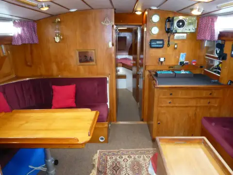 Moody 42 CC Ketch: saloon with burgundy U-shaped seating, varnished table and passage aft to the cabin