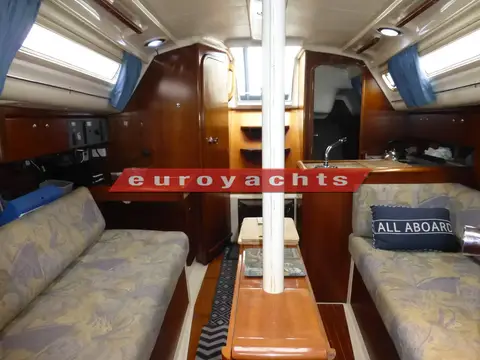 Moody S31: saloon looking aft past the mast support to chart table and galley, patterned settees