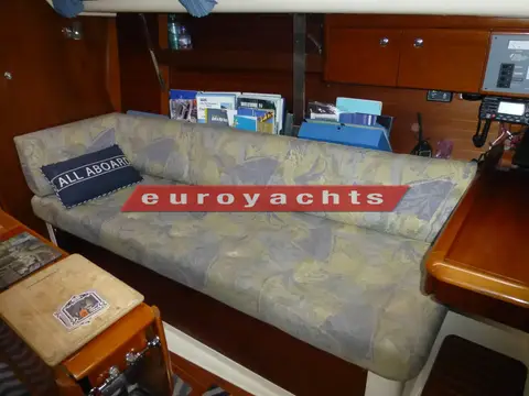 Moody S31: saloon settee berth with patterned upholstery and bookshelf above