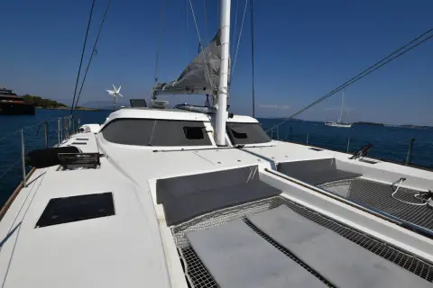 Nautitech 542: coachroof and foredeck trampolines looking forward, with the mast and calm bay beyond