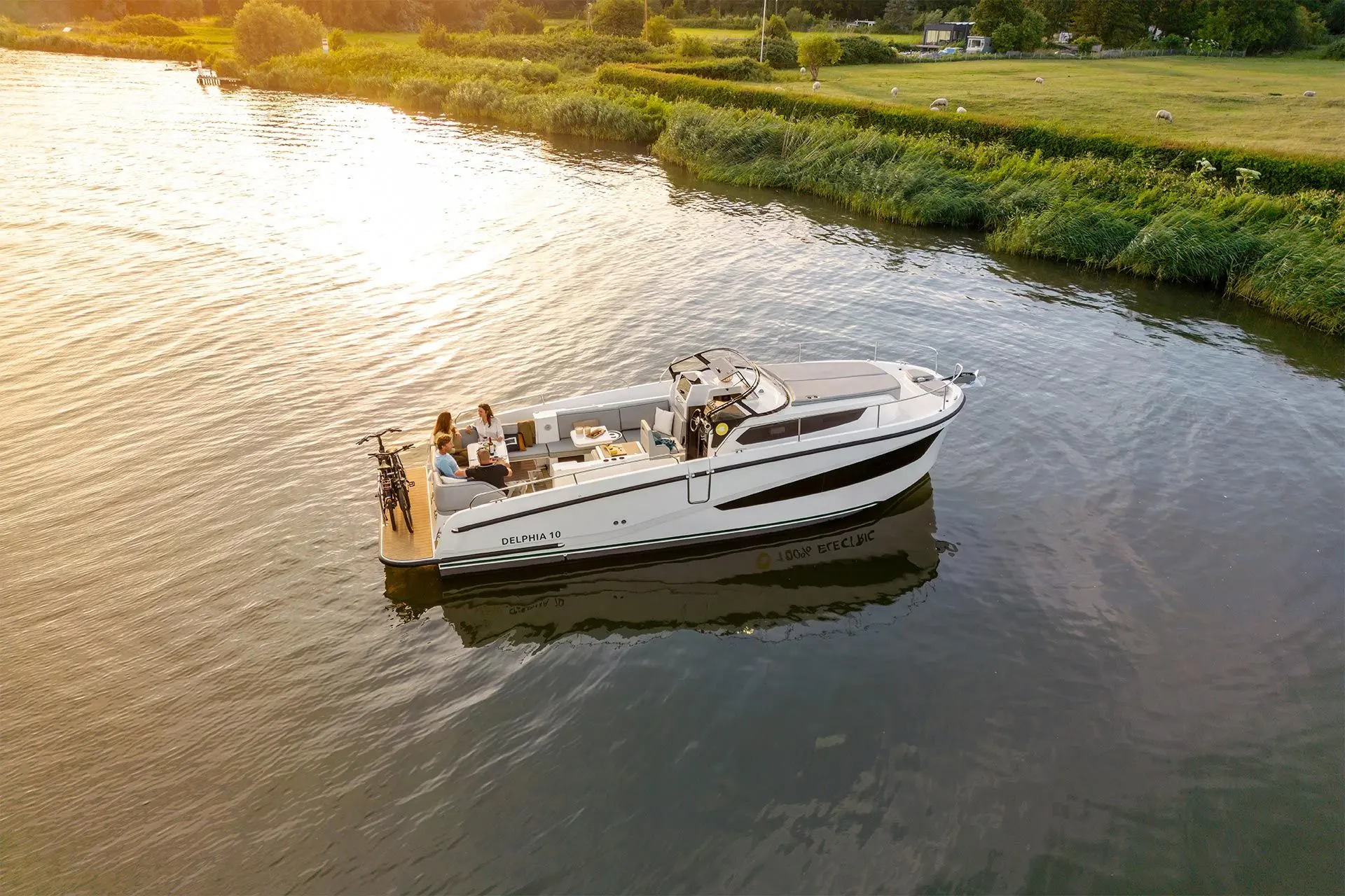 Delphia 10 Lounge: aerial view of the boat on a calm river at sunset, bicycles on the stern