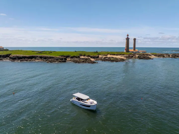 Delphia 10 Sedan: aerial view of the boat at anchor in front of a rocky island with two lighthouse towers