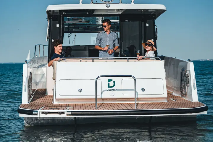 Delphia 11 Sedan: cockpit and teak bathing platform from astern, with three people at the open saloon doors