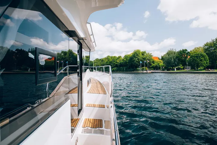 Delphia 12 FlyLounge: side deck with teak steps and guardrail running forward past large hull windows