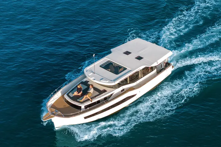 Delphia 12 Sedan: aerial view under way, two people relaxing on the forward sunbed with roof hatches visible