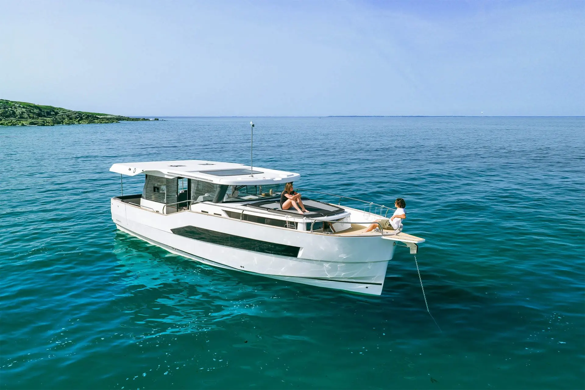 Delphia 12 Sedan: at anchor in clear water with people seated on the forward sunbed and bow