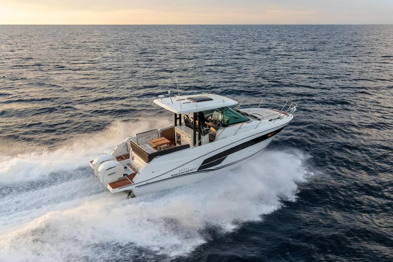Jeanneau Cap Camarat 10.5 WA Serie 2: underway at sea, aerial view of cockpit table, hardtop and twin outboard engines leaving a wake