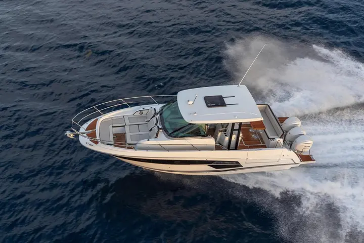 Jeanneau Cap Camarat 12.5 WA: aerial view under way at speed, showing bow seating, hardtop with sunroof and triple outboard engines