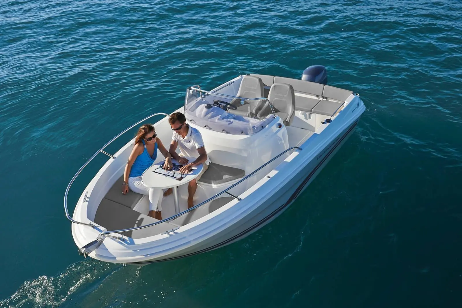 Jeanneau Cap Camarat 5.5 CC: aerial view of open deck with two people at a bow table, centre console and outboard