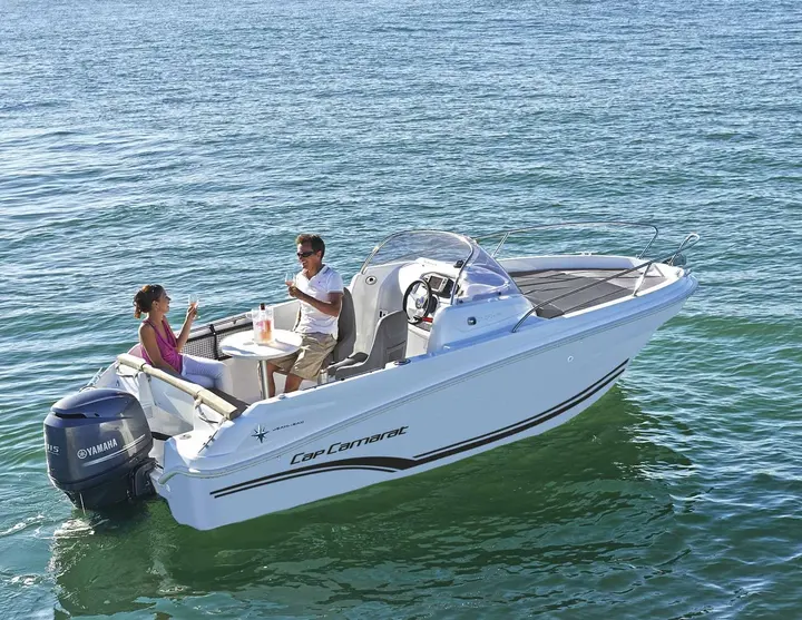 Jeanneau Cap Camarat 5.5 WA: aerial view of cockpit with table, helm seats, padded foredeck and Yamaha outboard engine