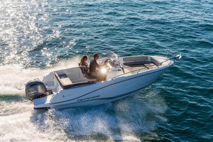 Jeanneau Cap Camarat 6.5 CC: aerial view underway showing helm console, two people seated, bow lounge and rear cockpit bench
