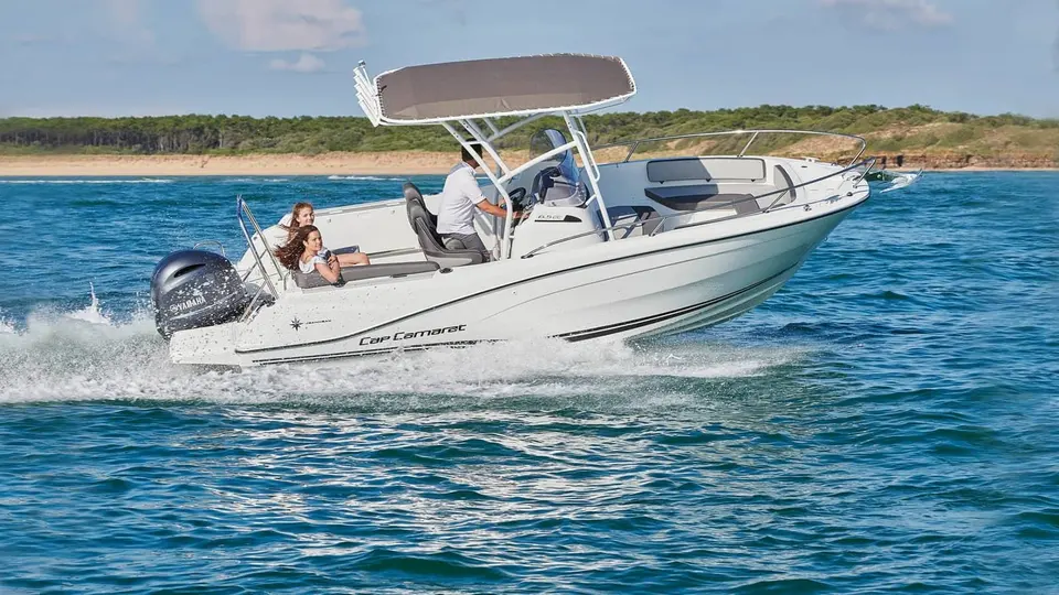 Jeanneau Cap Camarat 6.5 CC: underway at speed with grey T-top canopy, three people aboard at helm and cockpit seating