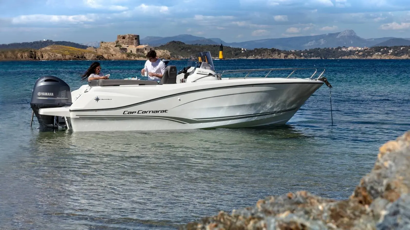Jeanneau Cap Camarat 6.5 CC: white centre console boat at anchor in shallow water, two people in cockpit, outboard engine at stern