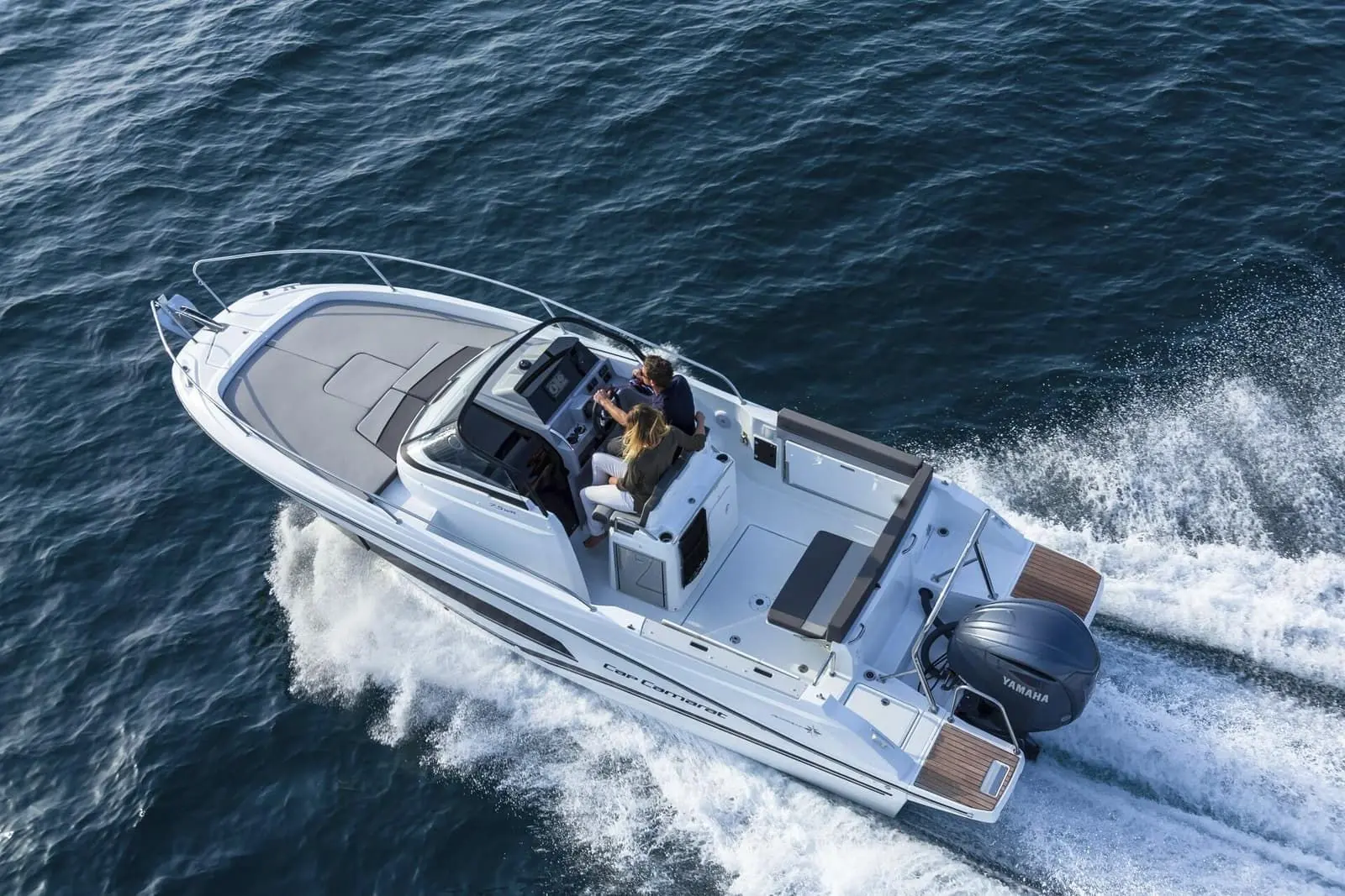 Jeanneau Cap Camarat 7.5 WA: aerial view under way showing foredeck sunpad, helm with two seated, aft cockpit and single outboard