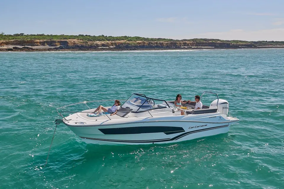 Jeanneau Cap Camarat 7.5 WA: boat at anchor in turquoise water, one person on the foredeck sunpad, two in the aft cockpit