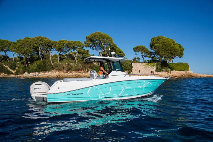Jeanneau Cap Camarat 9.0 CC Serie 2: side view under way with turquoise patterned hull, T-top helm and twin outboard engines