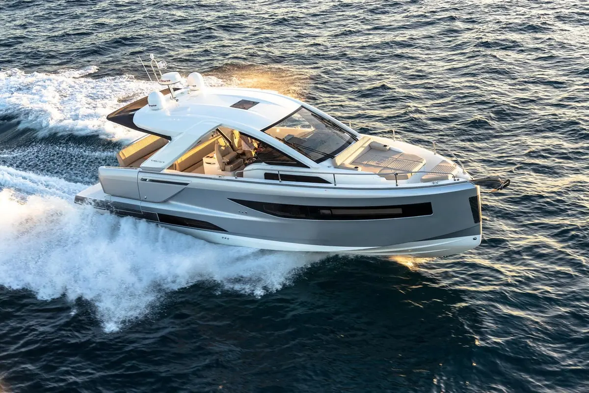 Jeanneau DB 37 IB: grey-hulled motor cruiser under way at speed, seen from above, with white hardtop and foredeck sunpad