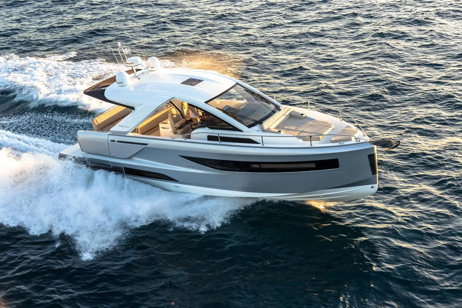 Jeanneau DB 37 IB: grey-hulled motor cruiser under way at speed, seen from above, with white hardtop and foredeck sunpad
