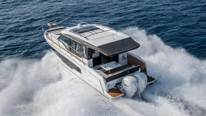 Jeanneau Merry Fisher 1095 Coupe SERIE2: aerial stern view at speed showing twin Yamaha outboards, cockpit table and extended hardtop canopy