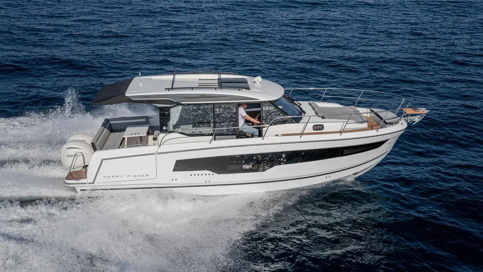 Jeanneau Merry Fisher 1095 Coupe SERIE2: side view underway with helmsman visible in wheelhouse, long hull window and bow rail