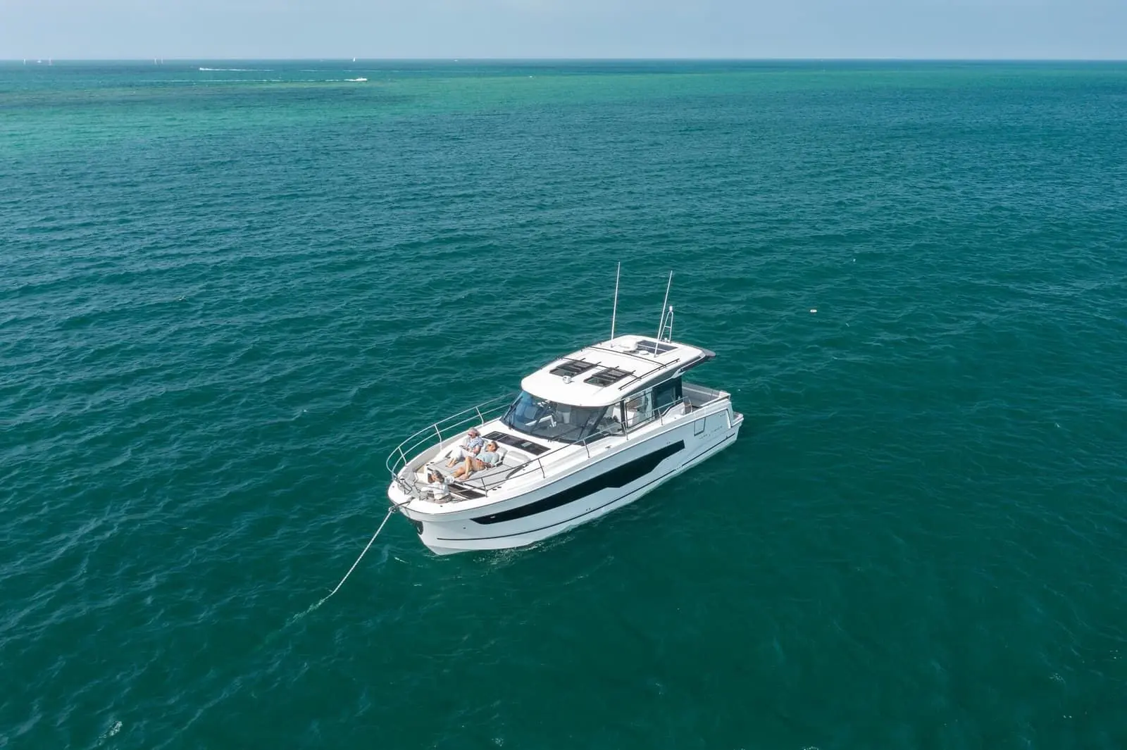 Jeanneau Merry Fisher 1295 Coupe: boat at anchor in open turquoise water, seen from above with people resting on the foredeck
