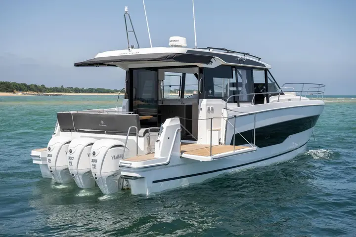 Jeanneau Merry Fisher 1295 Coupe: stern quarter view at sea showing three Yamaha outboards, side boarding platforms and enclosed wheelhouse