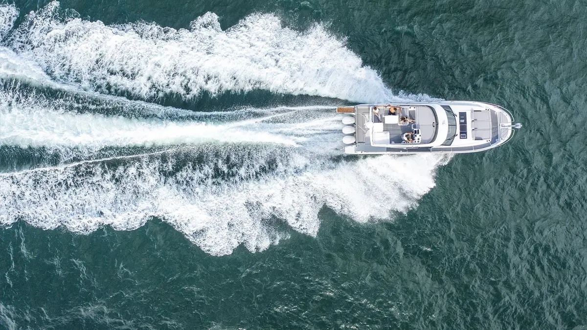 Jeanneau Merry Fisher 1295 Fly: aerial view from above of the motor boat under way, triple outboards leaving a wide white wake