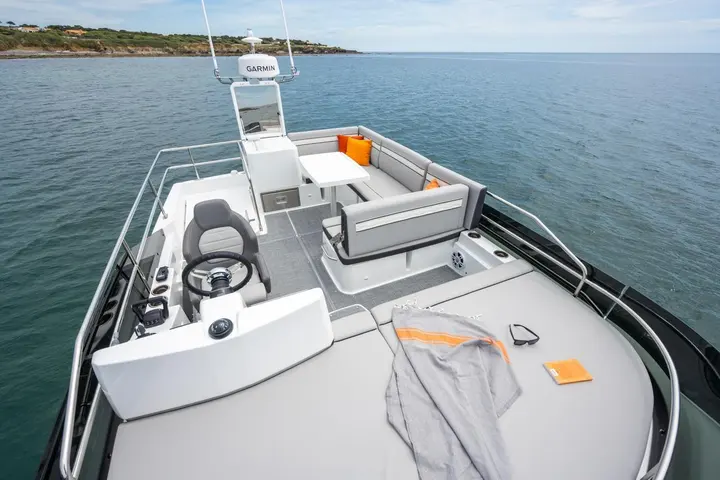 Jeanneau Merry Fisher 1295 Fly: flybridge with helm seat and wheel, U-shaped seating around a table, and a large sunbed at the front