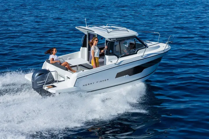Jeanneau Merry Fisher 605: white wheelhouse motorboat under way with outboard engine, two women in the open cockpit