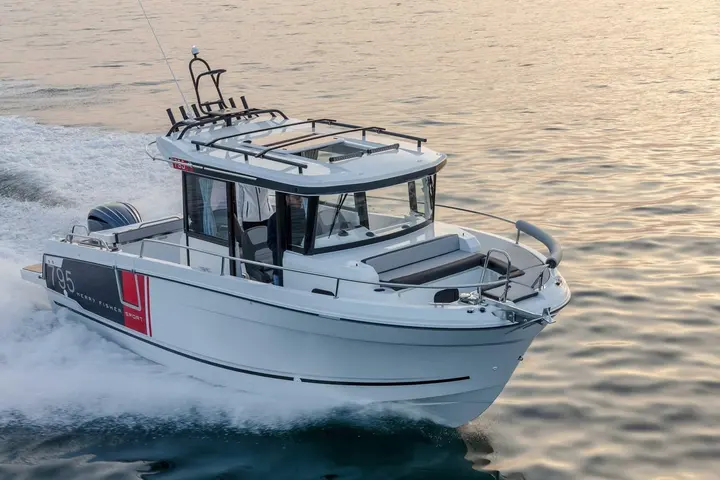 Jeanneau Merry Fisher 795 Sport: bow quarter view underway at dusk, showing foredeck sunpad, guardrails and wheelhouse with roof hatch