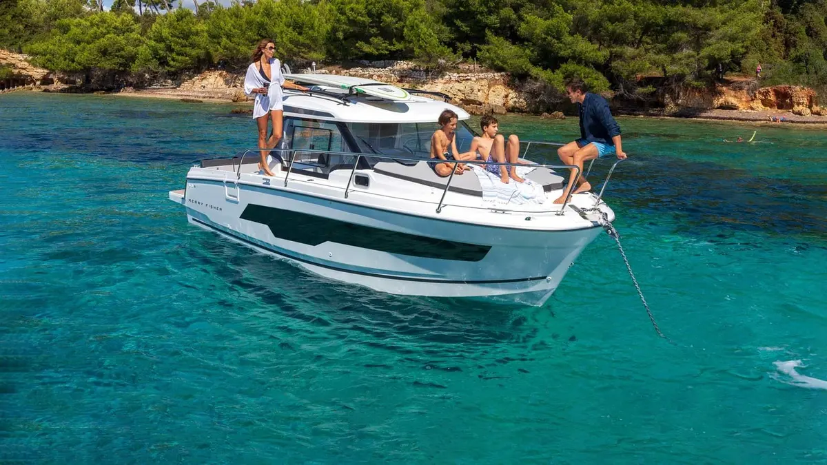 Jeanneau Merry Fisher 795: white motorboat at anchor in turquoise water, family relaxing on the foredeck and side deck
