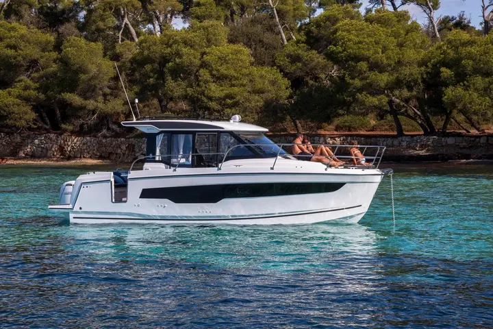 Jeanneau Merry Fisher 895 Serie 2: side profile at anchor showing wheelhouse, long hull window and people sunbathing on the foredeck