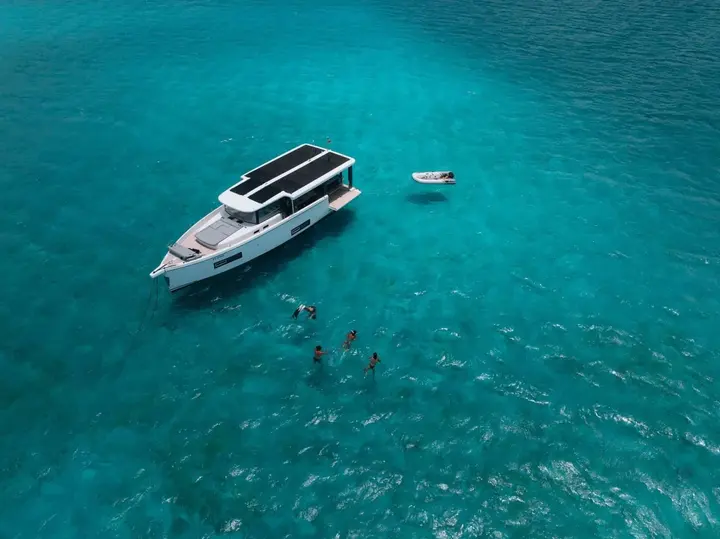 Jeanneau Sea Loft 480: aerial view at anchor in clear turquoise water, people swimming nearby and a tender alongside