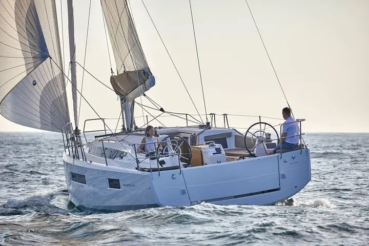 Jeanneau Sun Odyssey 410: under sail from astern, white hull, twin helm wheels and crew of two in the cockpit